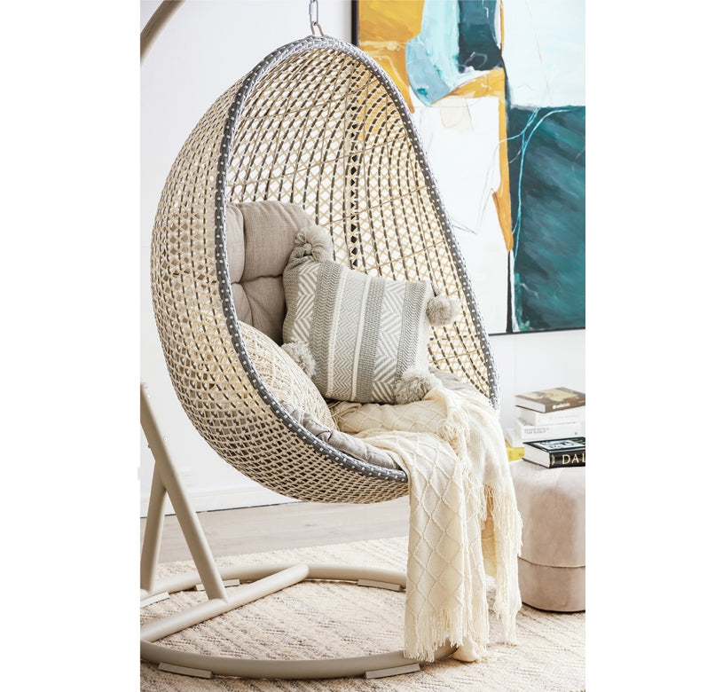 Woven egg-shaped chair with cushions and a blanket in a room  | Extraordinary Emporium UK setting.
