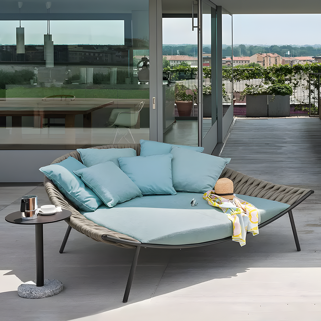 Modern outdoor patio with a lounge chair, cushions, and a small table. 
