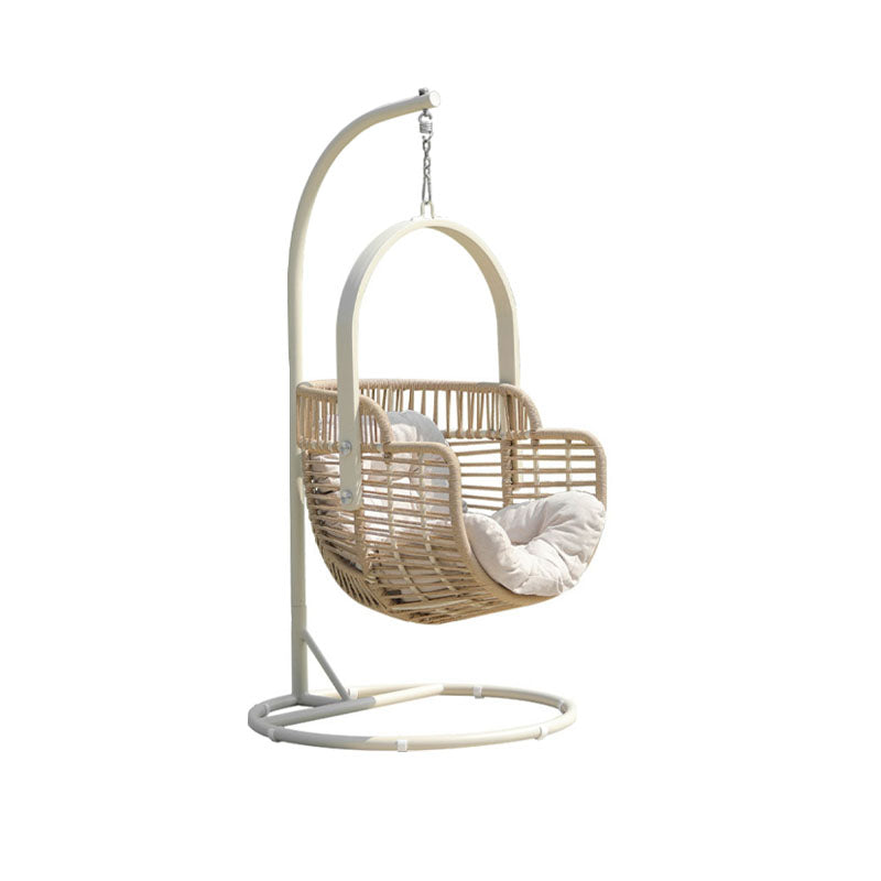 Wicker baby swing with white cushion on a stand against a white background