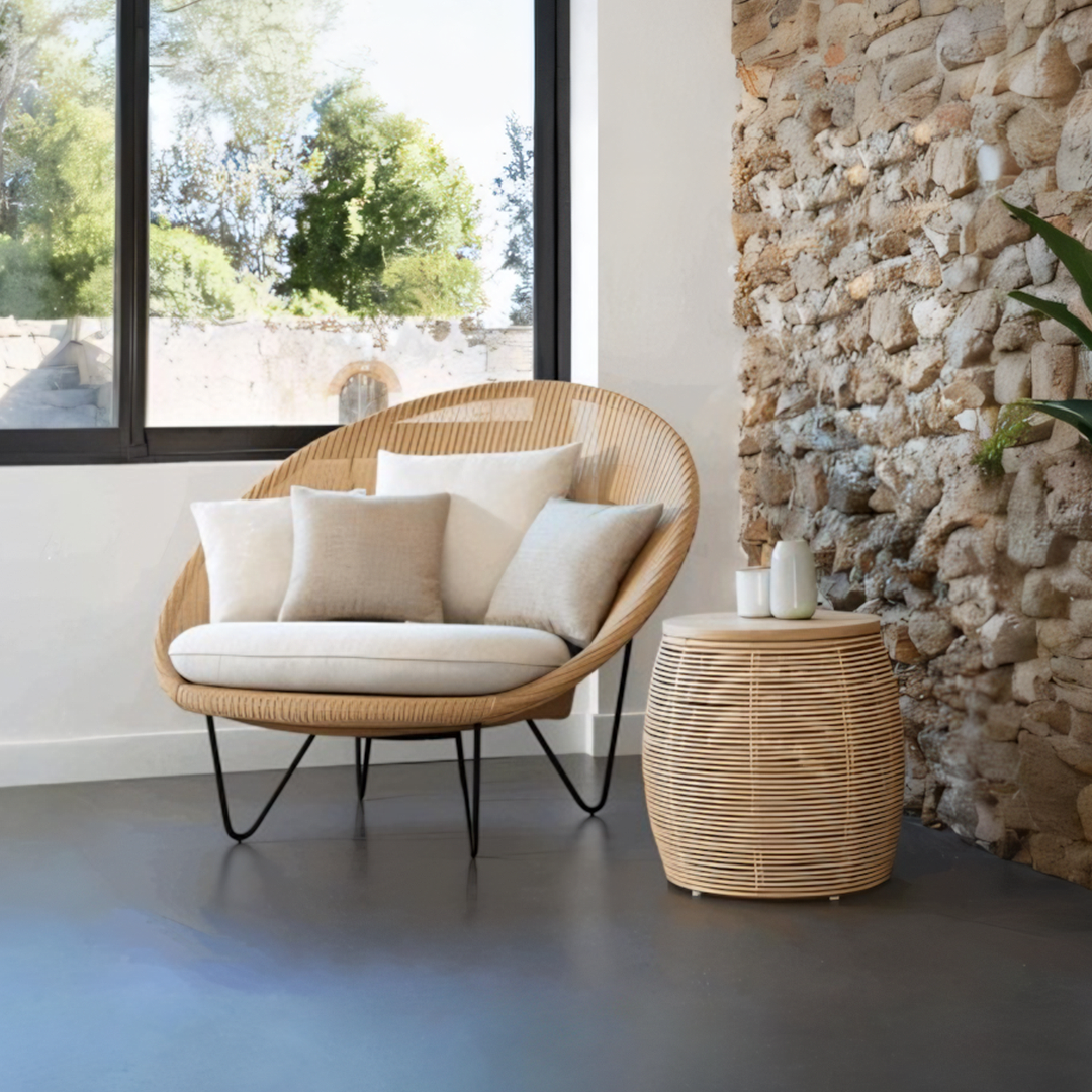 Wicker chair with cushions in a room with stone wall and large window  | Extraordinary Emporium UK
