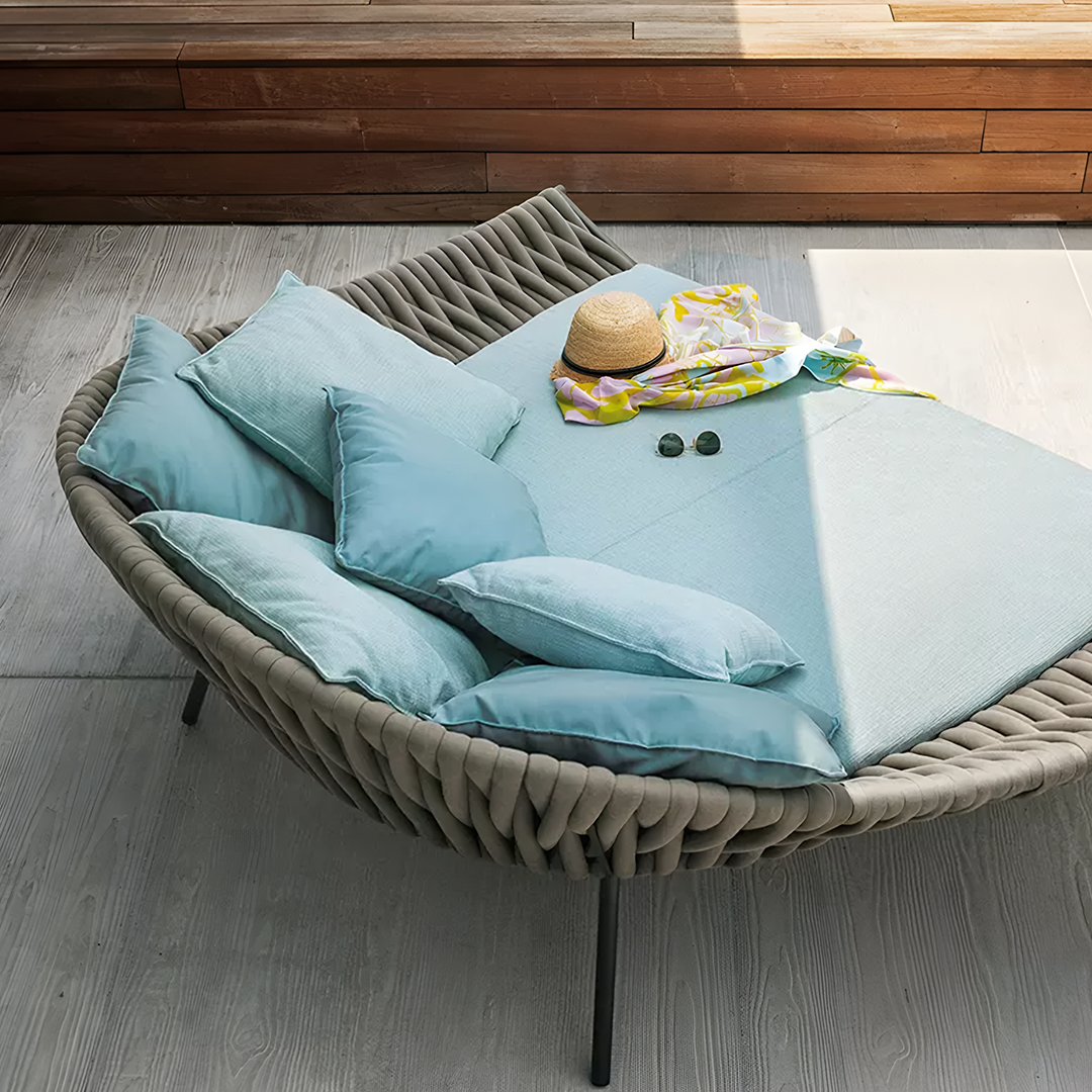 Woven chair with blue cushions and a hat on a wooden floor | Extraordinary Emporium UK