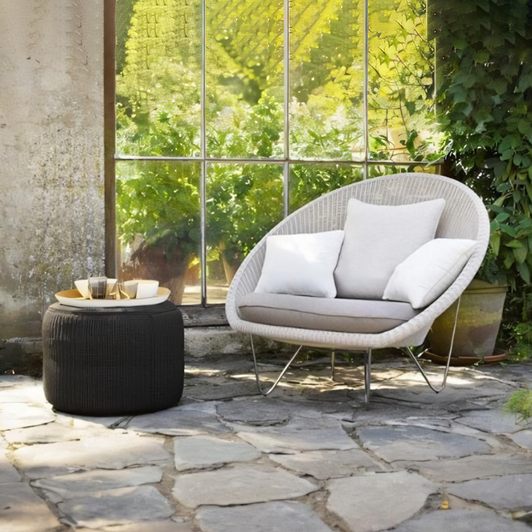 Outdoor patio setting with a wicker chair and ottoman on a stone patio.  | Extraordinary Emporium UK