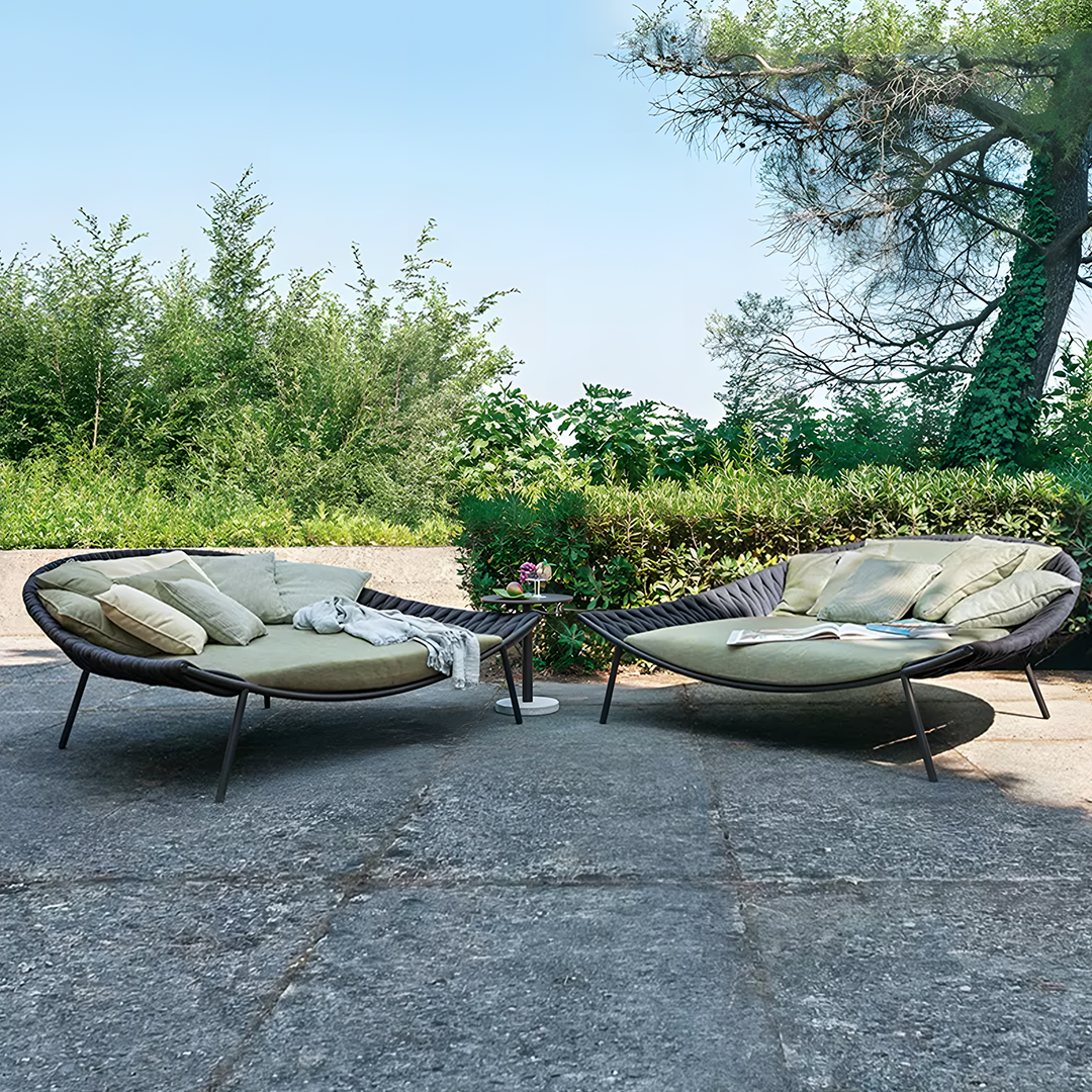 Outdoor patio furniture set with cushions on a stone patio, surrounded by greenery. | Extraordinary Emporium UK