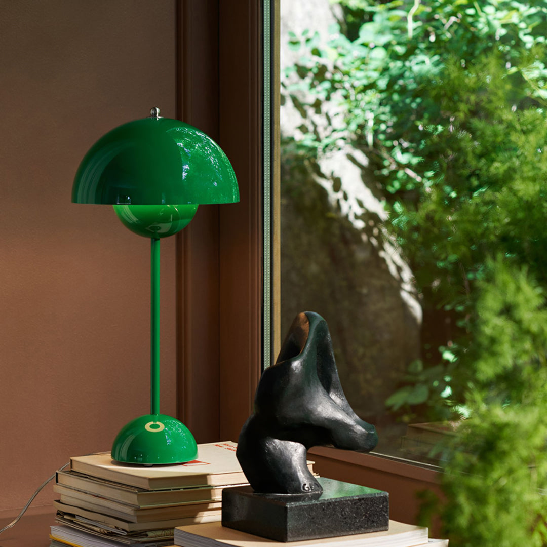 Green lamp on books with a sculpture and window view Extraordinary Emporium UK