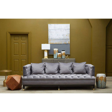 Gray sofa in a living room with a green wall and decorative items. | Extraordinary Emporium 