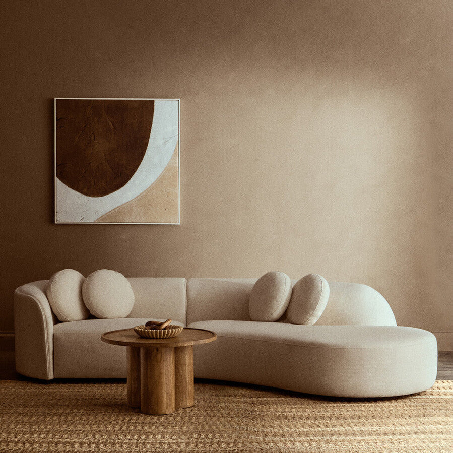 Modern living room with a beige sofa, wooden coffee table, and abstract wall art.| Extraordinary Emporium 