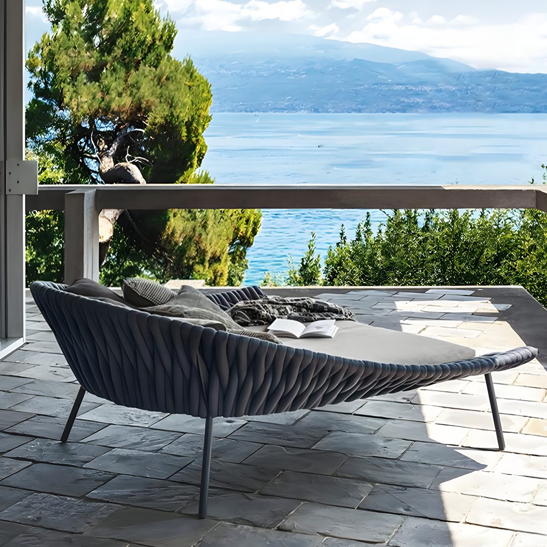 Modern outdoor sofa with cushions on a patio overlooking a scenic lake. | Extraordinary Emporium UK