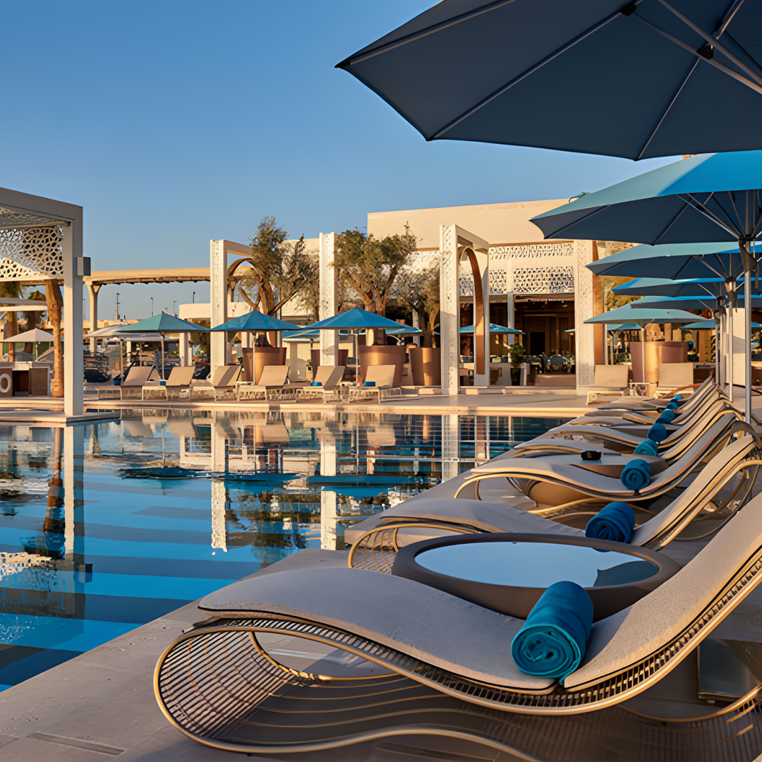 Poolside area with lounge chairs and umbrellas at a resort.| Extraordinary Emporium 