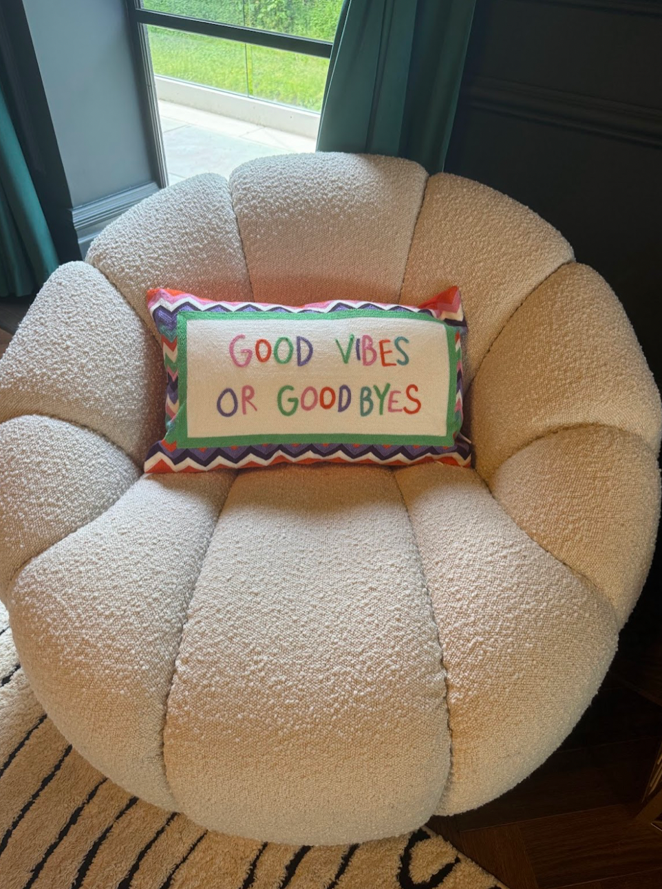 Round beige cushion with a colorful pillow reading 'Good Vibes or Goodbyes' on a chair. | Extraordinary Emporium