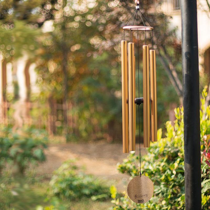 Bronze wind chime hanging outdoors with a garden background  | Extraordinary Emporium UK
